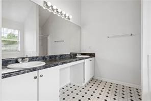 full bath featuring double vanity, baseboards, vaulted ceiling, and a sink