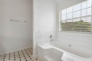 full bathroom featuring baseboards and a bath