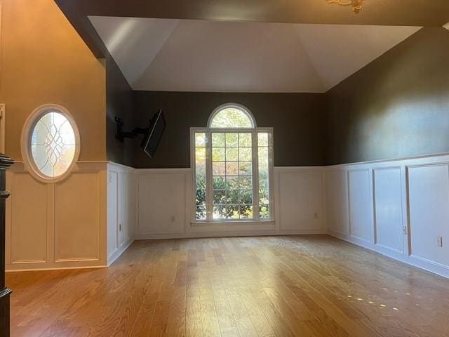 bonus room with light wood-type flooring and high vaulted ceiling