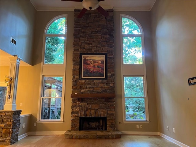 living room featuring ornamental molding, a towering ceiling, and a stone fireplace