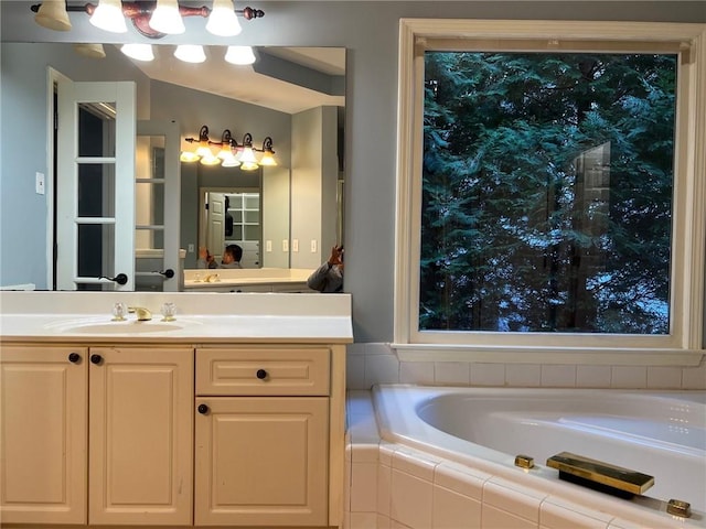 bathroom with vanity and tiled tub