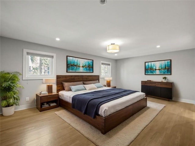 bedroom with baseboards, multiple windows, and light wood finished floors