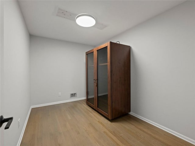 unfurnished bedroom featuring visible vents, light wood-style flooring, and baseboards