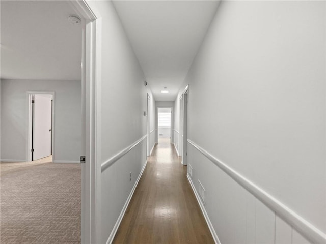 hall featuring carpet flooring and a decorative wall