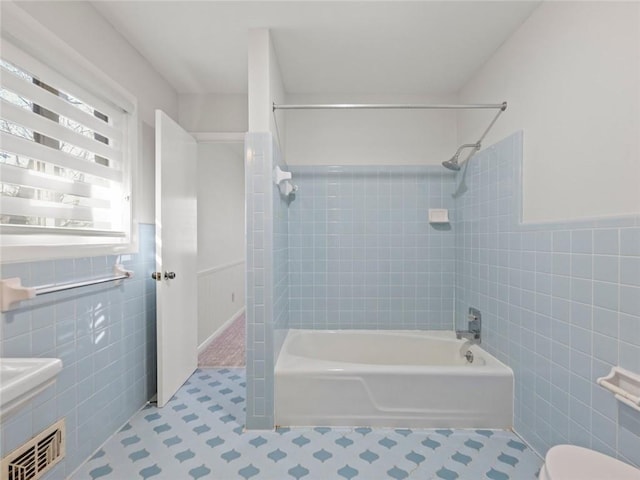 bathroom with tile walls, visible vents, wainscoting, shower / tub combination, and tile patterned floors