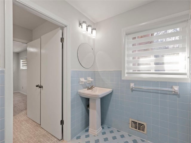 bathroom with visible vents, tile walls, and wainscoting