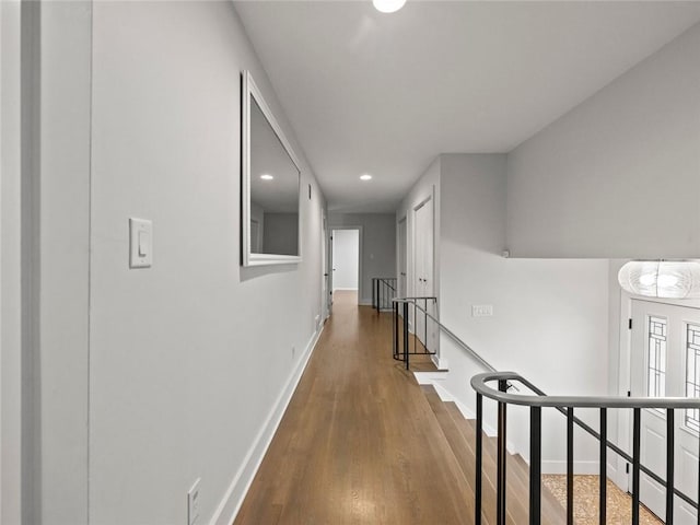 hall with recessed lighting, wood finished floors, an upstairs landing, and baseboards