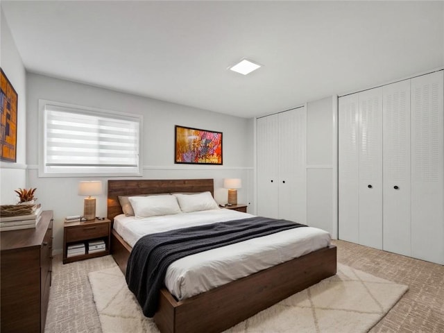 bedroom featuring multiple closets and light colored carpet