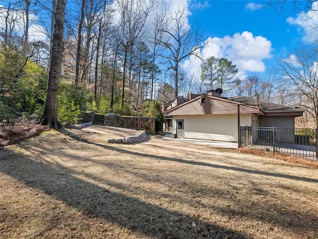 view of side of property featuring fence and a lawn