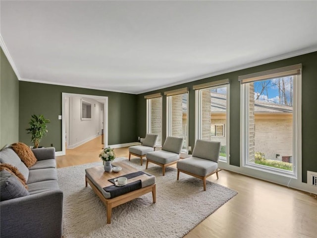 living area with baseboards, light wood-style flooring, and crown molding