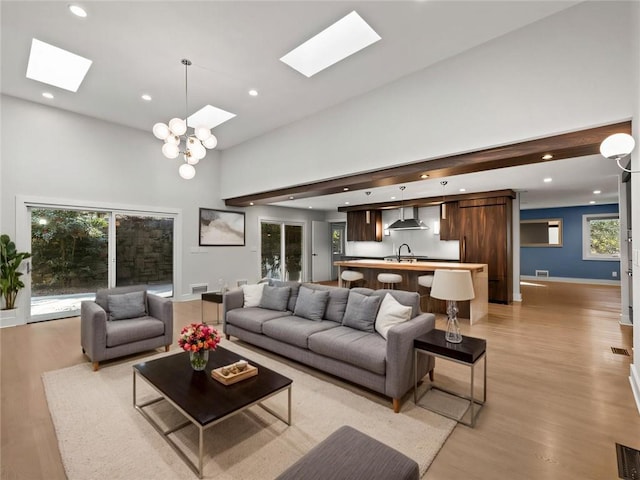 living room featuring recessed lighting, a skylight, a towering ceiling, baseboards, and light wood-style floors