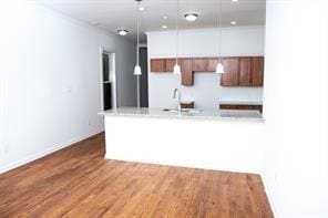 kitchen featuring hardwood / wood-style flooring, sink, hanging light fixtures, and white cabinets