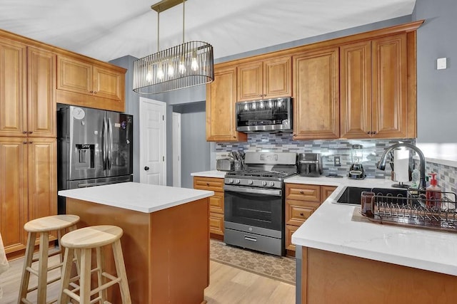 kitchen featuring tasteful backsplash, stainless steel appliances, an inviting chandelier, light hardwood / wood-style floors, and a kitchen island