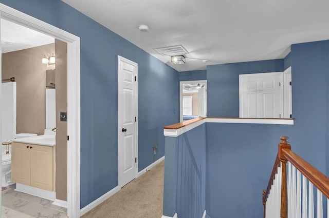 hallway with sink and light colored carpet