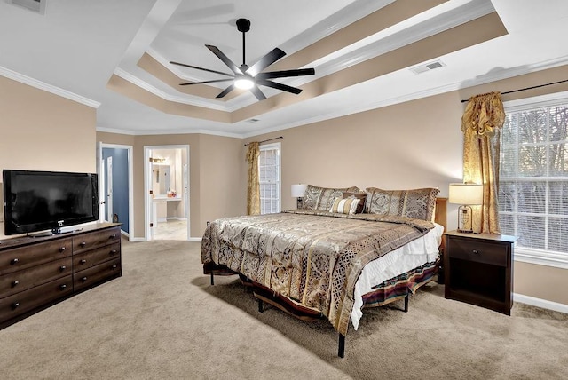 bedroom with a raised ceiling, ceiling fan, ornamental molding, connected bathroom, and light colored carpet