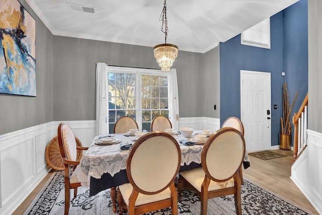 dining room with ornamental molding, plenty of natural light, a chandelier, and light hardwood / wood-style flooring