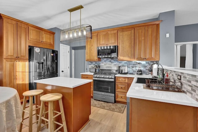 kitchen featuring backsplash, stainless steel appliances, sink, decorative light fixtures, and a kitchen island