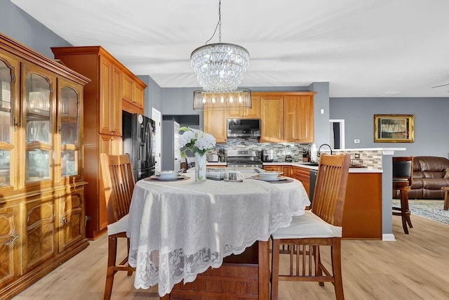 dining space with a notable chandelier, sink, and light hardwood / wood-style flooring