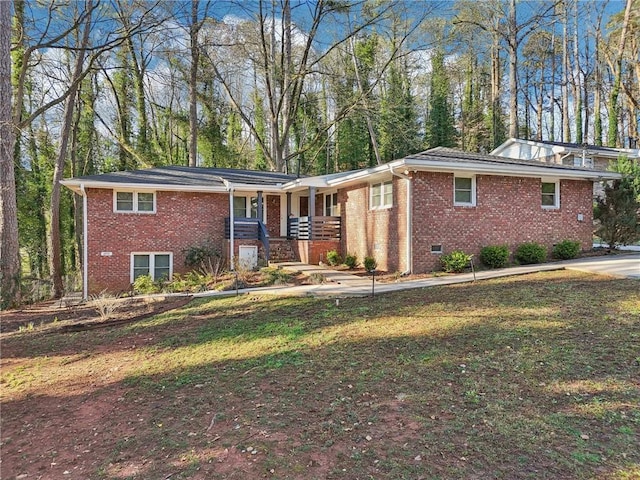 view of front of house featuring a front yard, covered porch, brick siding, and crawl space