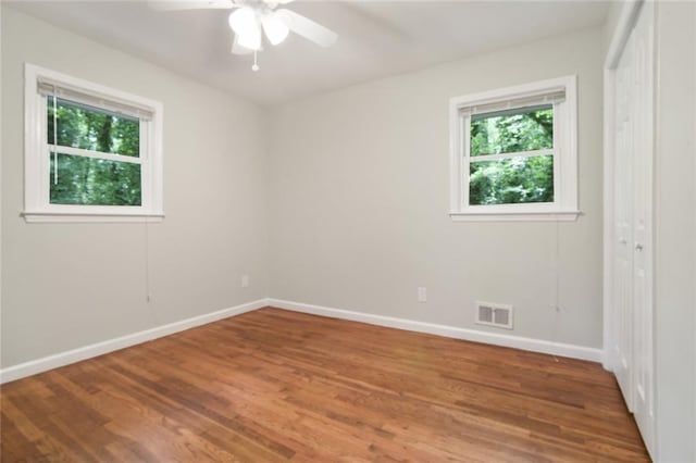 empty room featuring visible vents, ceiling fan, baseboards, and wood finished floors