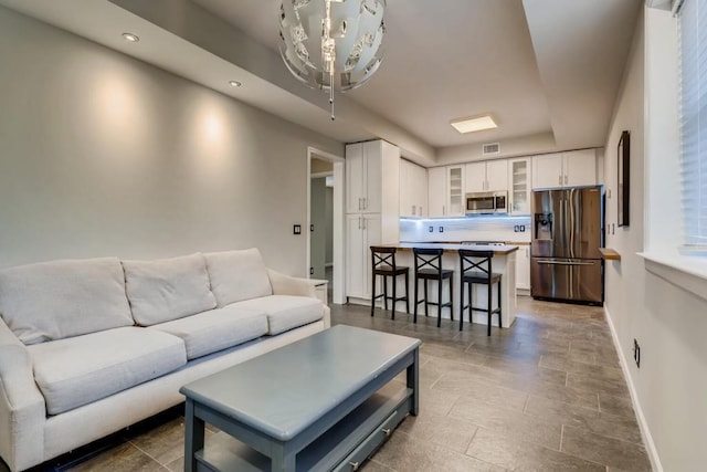 living area with recessed lighting, visible vents, and baseboards