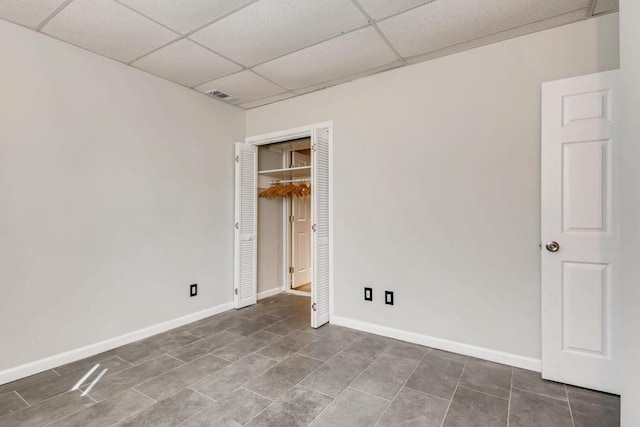 unfurnished bedroom featuring a paneled ceiling, visible vents, a closet, and baseboards