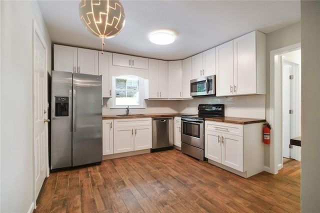 kitchen featuring a sink, dark wood finished floors, white cabinetry, stainless steel appliances, and wooden counters