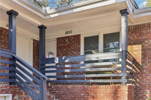 view of exterior entry with brick siding and covered porch