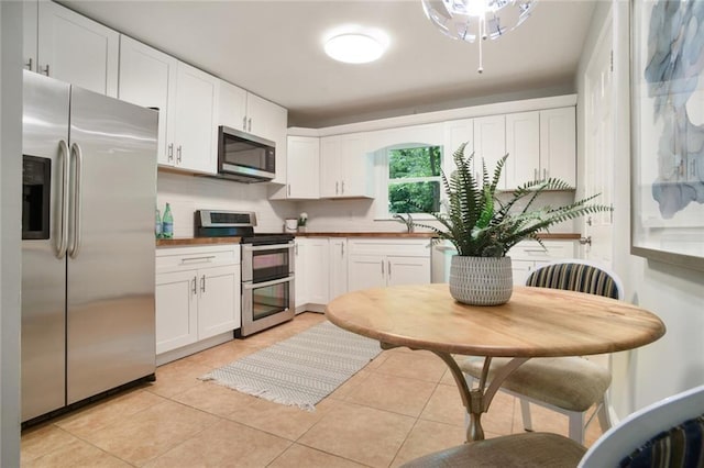 kitchen featuring light tile patterned floors, stainless steel appliances, white cabinets, and decorative backsplash