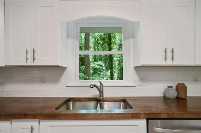 kitchen featuring white cabinetry, decorative backsplash, wooden counters, and a sink