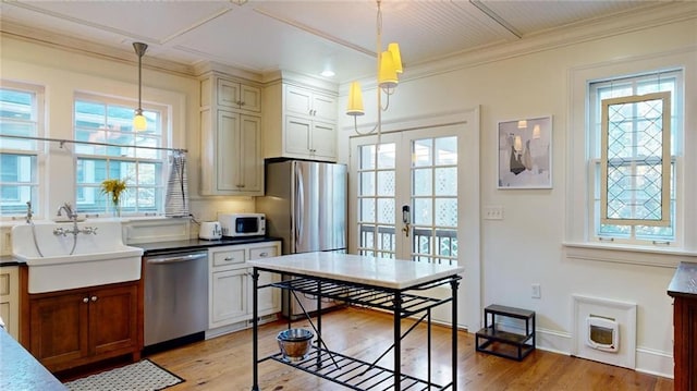 kitchen with pendant lighting, appliances with stainless steel finishes, sink, and french doors