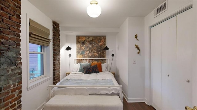 bedroom featuring brick wall, dark hardwood / wood-style floors, and a closet