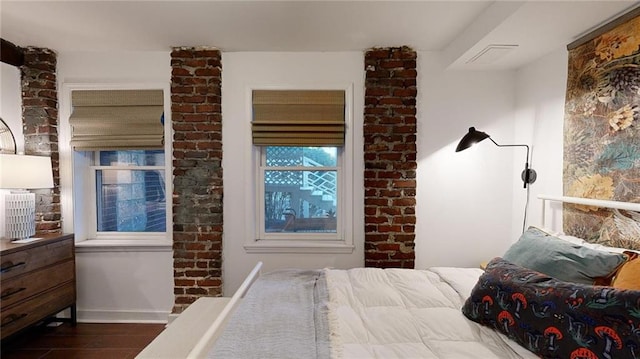 bedroom featuring brick wall and wood-type flooring