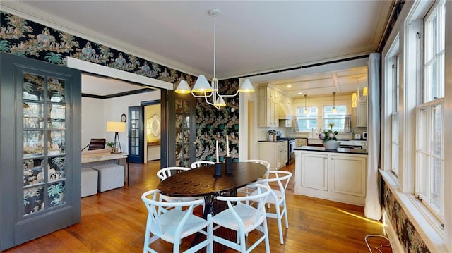 dining area with crown molding, an inviting chandelier, and light hardwood / wood-style flooring