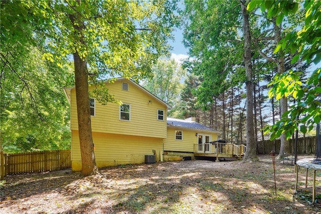 rear view of property featuring a trampoline, a deck, and central air condition unit