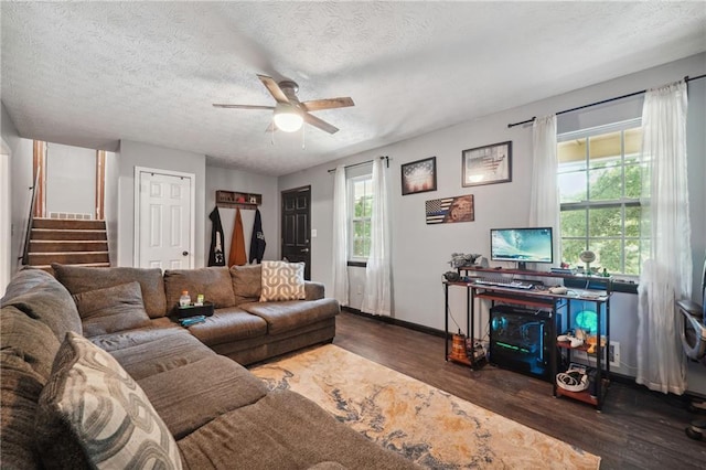 living room featuring ceiling fan, dark wood-type flooring, and a textured ceiling