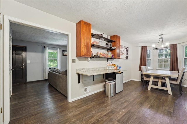 kitchen with a breakfast bar, dark hardwood / wood-style flooring, pendant lighting, and a textured ceiling