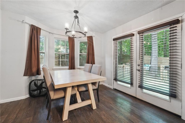 dining area with a textured ceiling, dark wood-type flooring, a healthy amount of sunlight, and a notable chandelier