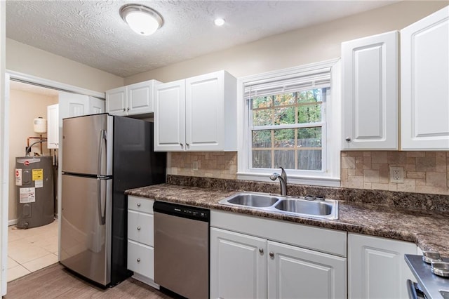 kitchen with stainless steel appliances, sink, electric water heater, a textured ceiling, and white cabinets