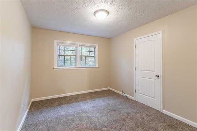 carpeted empty room featuring a textured ceiling