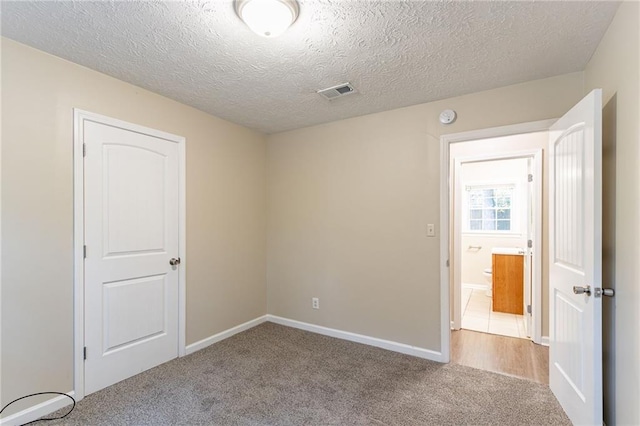 carpeted empty room with a textured ceiling