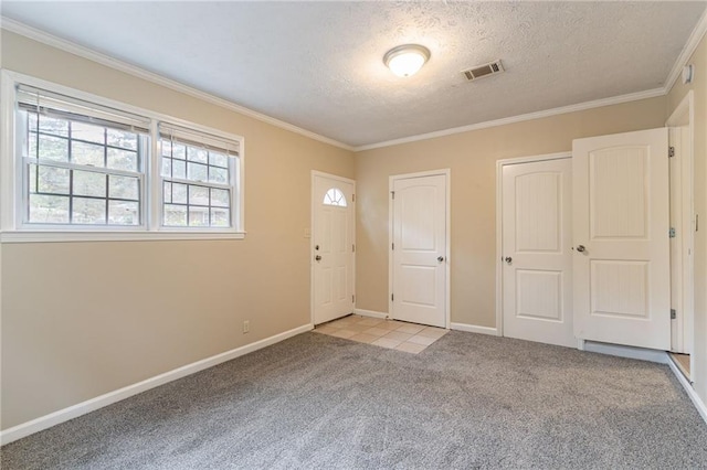 carpeted foyer entrance with a textured ceiling and ornamental molding