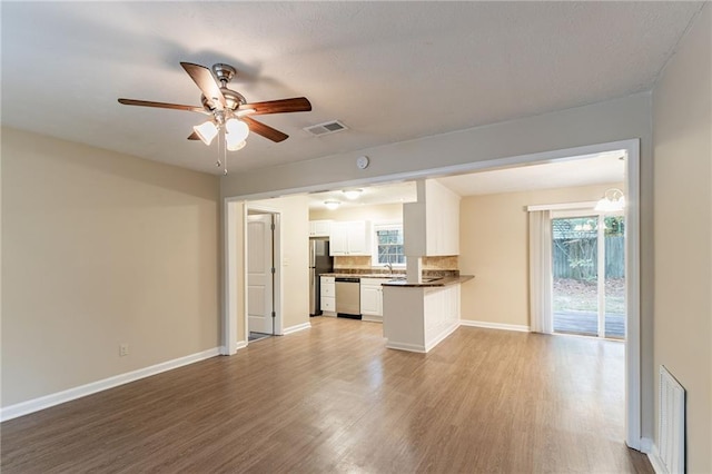 unfurnished living room with light wood-type flooring, sink, and ceiling fan with notable chandelier