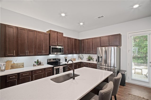 507 Bishop Ln, Woodstock, GA 30188 - kitchen with appliances with stainless steel finishes, a sink, a kitchen breakfast bar, decorative backsplash, and dark brown cabinets