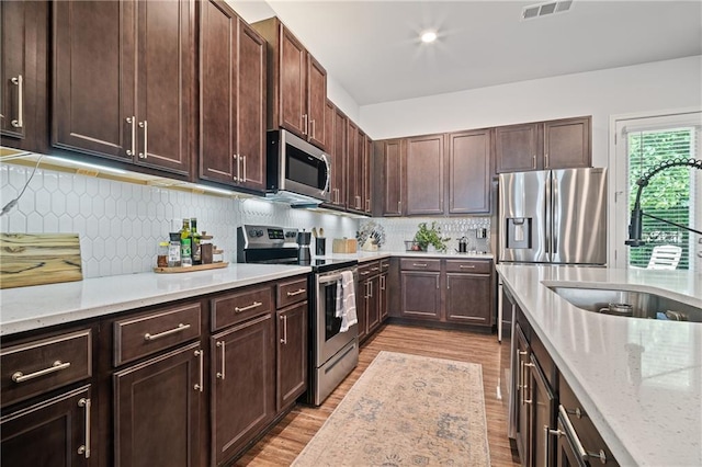 507 Bishop Ln, Woodstock, GA 30188 - kitchen with appliances with stainless steel finishes, a sink, light wood-type flooring, and light stone countertops