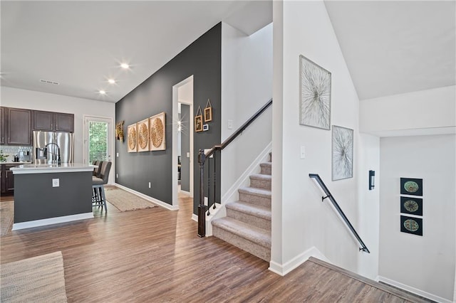507 Bishop Ln, Woodstock, GA 30188 - kitchen with dark brown cabinetry, stainless steel fridge, light countertops, an island with sink, and wood finished floors