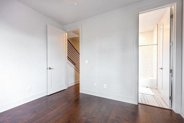 unfurnished room featuring baseboards, wood-type flooring, and stairs