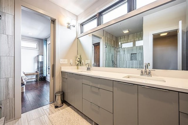 full bathroom featuring a tile shower, double vanity, and a sink