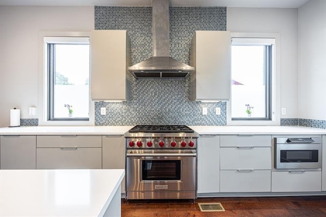 kitchen with visible vents, light countertops, appliances with stainless steel finishes, wall chimney range hood, and modern cabinets