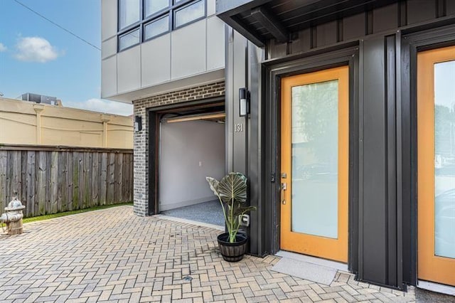 doorway to property featuring fence, brick siding, and board and batten siding